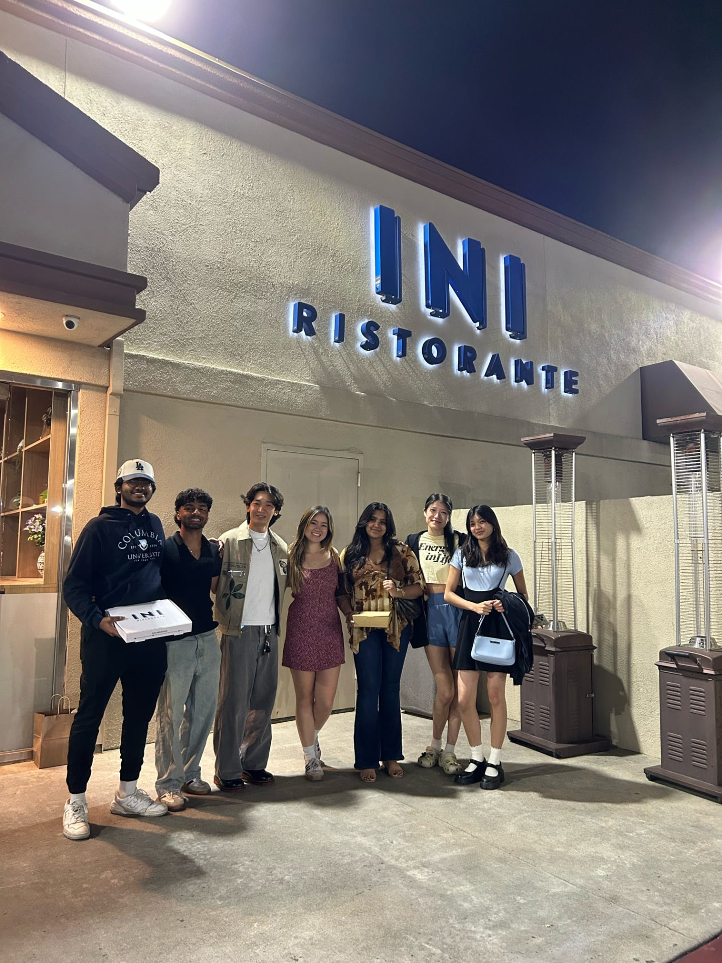 Seven chapter members outside a restaurant at night
