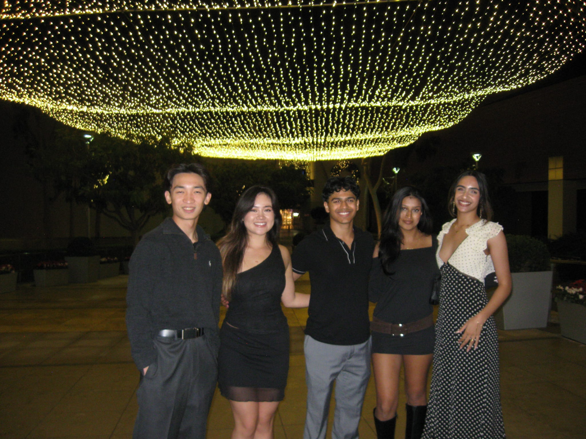 Five chapter members under string lights at a formal