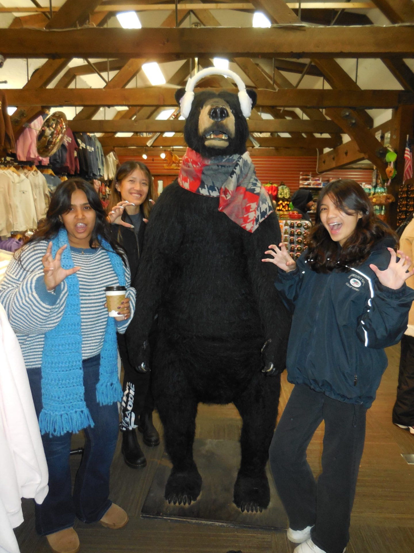 Three chapter members posing with a bear statue